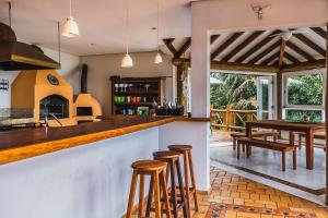 cocina con barra, mesa y sillas en Casa de luxo com vista para o mar em Ilhabela, en Ilhabela