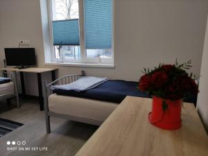 a bedroom with a bed and a table with a vase of flowers at Pokoje nad Regalicą in Szczecin