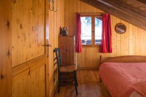 ein Schlafzimmer mit einem Bett, einem Fenster und einem Stuhl in der Unterkunft Mont Blanc Apartments in Morgex