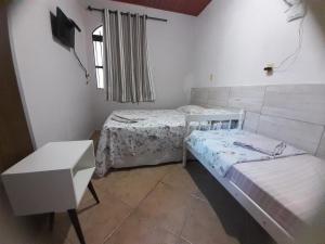 a small bedroom with two beds and a window at Casinha do Trapiche in Penha