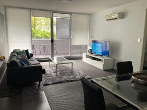 a living room with a couch and a tv at North Sydney Wyndel Apartments-MIL1005 in Sydney