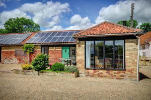 une maison en briques avec des panneaux solaires sur le toit dans l'établissement East Green Farm Cottages - The Granary, à Saxmundham