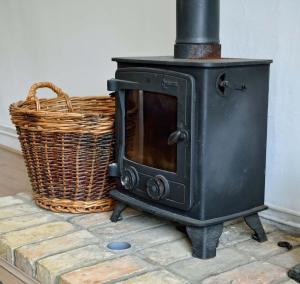 - un poêle noir et un panier sur un sol en briques dans l'établissement East Green Farm Cottages - The Granary, à Saxmundham 33 autres photos