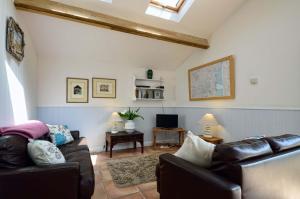 a living room with two leather couches and a tv at East Green Farm Cottages - Gardeners Cottage in Saxmundham