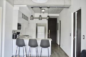 a kitchen with three chairs and a kitchen island at Cozy Stays Cayala Apartments 4 in Guatemala