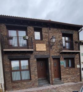 a brick building with windows and a balcony at Puente viejo de Buitrago casa Enebro in Buitrago del Lozoya
