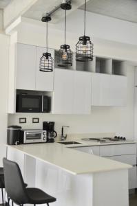 a kitchen with white cabinets and black chairs at Cozy Stays Cayala Apartments 4 in Guatemala