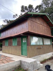 a wooden house with a green door in front of it at Casa Alternativa Pedacinho do Céu in Urubici