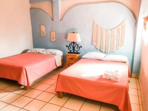 Cette chambre comprend 2 lits avec des draps orange. dans l'établissement Colibri Hotel, à Cabo Corrientes