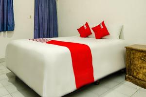 a white bed with red pillows in a room at OYO Hotel Cabo Del Sur, Cabo San Lucas in Cabo San Lucas