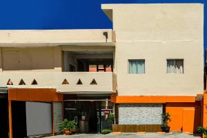 um edifício de apartamentos com uma fachada laranja e branca em OYO Hotel Cabo Del Sur, Cabo San Lucas em Cabo San Lucas
