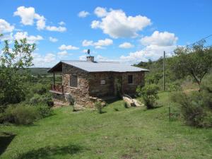 a stone house with a roof on a field at Cabaña Panambi in Villa Serrana +61 photos