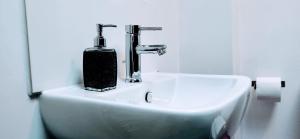 a bathroom sink with a soap dispenser on it at Brookside 2BR Flat Oxford City Centre Free Parking in Oxford