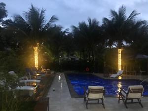 een zwembad met stoelen en palmbomen in de nacht bij Perequê-Açu Aparts in Paraty