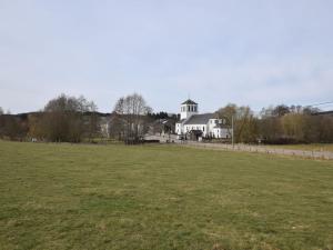 a large field with a white house in the background at Charming Holiday Home in Sainte Ode with Terrace in Amberloup