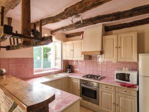 uma cozinha com balcões de azulejos cor-de-rosa e um forno com placa de fogão em Superb holiday home with pool em Cressensac