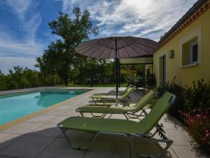 a group of lawn chairs and an umbrella next to a pool at Delightful Holiday Home in Gindou with Private Swimming Pool in Gindou