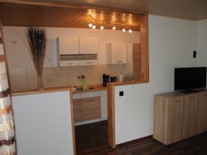 eine Küche mit weißen Schränken und einem TV in der Unterkunft Apartment in the Bavarian Forest with balcony in Drachselsried