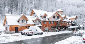 a ski lodge with cars parked in the snow at Apartman Pustolov - Stara planina in Crni Vrh