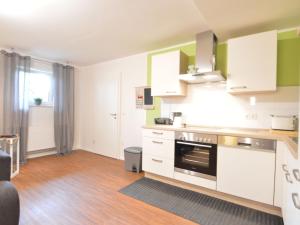 a kitchen with white cabinets and a stove at Spacious apartment in the Vulkaneifel in Ulmen