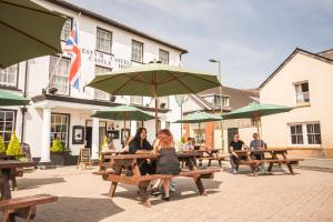 a group of people sitting at picnic tables with umbrellas at The Castle Hotel in Llandovery