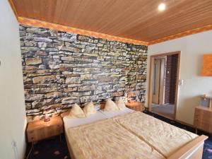 LangenbachにあるCozy holiday home in Schwarzbach Thuringia with gardenの石壁のベッドルーム1室、ベッド1台が備わります。