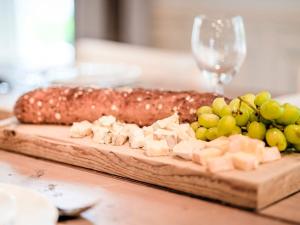 a cutting board with cheese and grapes and a bread at Gorgeous Farmhouse with Sauna in Noardburgum in Noordbergum