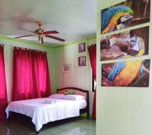 um quarto com uma cama e uma pintura de papagaios em RedDoorz @ Garcia Hernandez Bohol em Garcia Hernandez