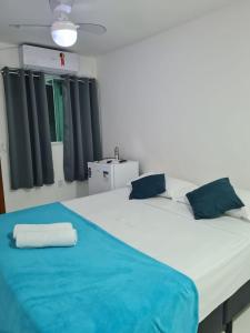 a large white bed with a blue blanket on it at Suites Golfo in Abraão
