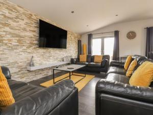 a living room with leather furniture and a brick wall at Box Tree Escapes in Lancaster