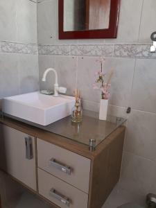 eine Badezimmerablage mit Waschbecken und Spiegel in der Unterkunft El Shaday in Itanhaém