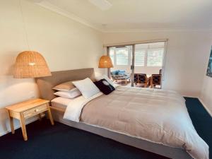 a bedroom with a large bed with two lamps at Bombora in Callala Beach