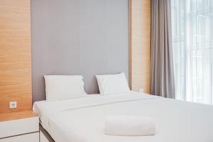ein Schlafzimmer mit einem weißen Bett und einem Fenster in der Unterkunft Great Choice 1BR at Brooklyn Alam Sutera Apartment By Travelio in Dongkal Dua + 13 Fotos