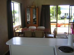 Rotoiti的住宿－The Lakehouse Bach - Lake Rotoiti Bach，厨房配有桌椅和窗户。
