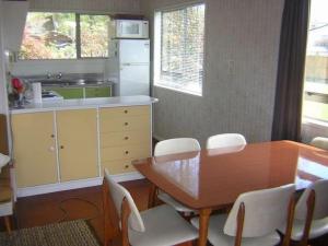 a kitchen with a wooden table and white chairs at The Lakehouse Bach - Lake Rotoiti Bach in Rotoiti