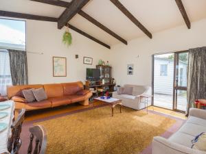 a living room with a couch and a table at Kiwi Bach at Omaha - Omaha Holiday Home in Omaha