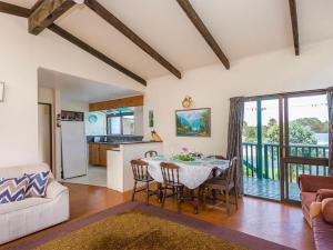 a kitchen and living room with a table and chairs at Kiwi Bach at Omaha - Omaha Holiday Home in Omaha