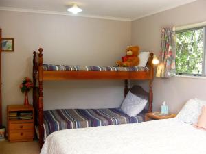 um quarto com 2 beliches e um ursinho de peluche em Fernleigh - Moetapu Bay Holiday Home em Whatanihi