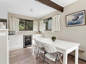 une cuisine blanche avec une table et des chaises blanches dans l'établissement Lake House and Studio - Lake Rotoiti Holiday Home, à Okere Falls 17 autres photos