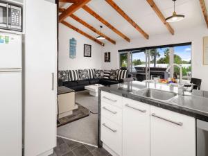 a kitchen with white cabinets and a living room at Fantail Cottage - Lake Rotoiti Holiday Home in Rotoiti