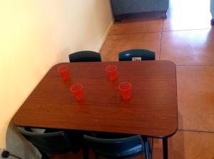 a wooden table with four orange cups on it at El Kedira - Campbells Beach Holiday Home in Tawharanui