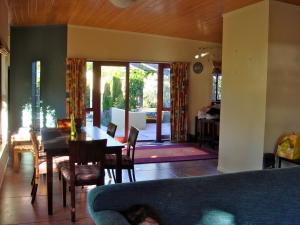 een woonkamer met een bank en een tafel en stoelen bij El Kedira - Campbells Beach Holiday Home in Tawharanui