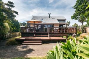 Casa con terraza con bancos y sombrilla en Olive Lane - Waiheke Island, en Onetangi