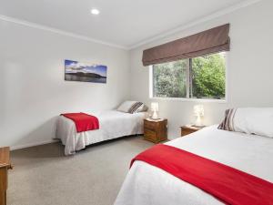 a bedroom with two beds and a window at Te Miro Cottage - Lake Tarawera Cottage in Lake Tarawera