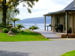 a house with a porch with a view of the water at Te Miro Cottage - Lake Tarawera Cottage in Lake Tarawera +20 photos