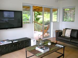 a living room with a tv and a couch and a table at Tiromoana - Mathesons Bay Holiday Home in Leigh