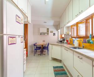 サンパウロにあるMADÁ hostelの白いキャビネットとテーブル付きのキッチンが備わります。