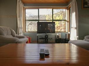 a living room with a wooden table and a television at Tranquil Tipperary - Arrowtown Holiday Home in Arrowtown