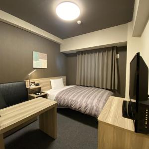 a hotel room with a bed and a television at Route Inn Grantia Tokai Spa&Relaxation in Tokai