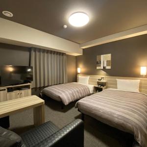 東海市にあるルートイン グランティア東海Spa & Relaxationのベッド2台とテレビが備わるホテルルームです。